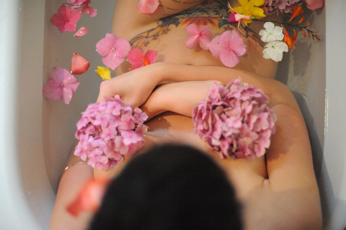 Голая женщина в ванной с цветами